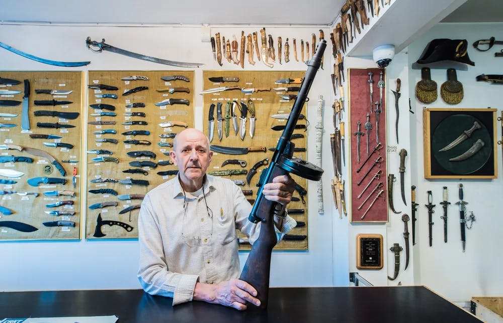 Vapenhandlaren William Wadstein visar upp en deaktiverad Suomi-maskinpistol. I affären finns ett brett sortiment av högkvalitativa knivar. 
